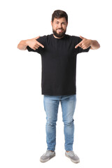 Wall Mural - Handsome man pointing at black t-shirt on white background