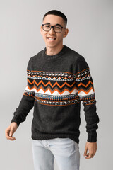 Sticker - Handsome young Asian man in knitted sweater on grey background