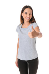 Wall Mural - Pretty young woman in stylish t-shirt showing thumb-up on white background
