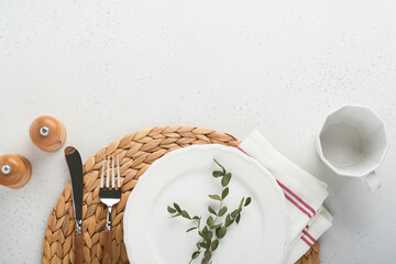 Wall Mural - Vintage zero waste silverware. Rustic vintage set of white plate, wooden spoon and fork on napkin for dishes from water hyacinth on light gray concrete background. Empty dishes. Top view. Mock up.