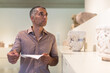 © JackF - Adult man is visiting museum and looking at the exposition with information brochure indoor.