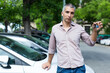 © JackF - Adult man is holding key and standing near his modern car outdoor.