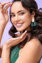 Pretty Young Woman With Glitters On Her Face Against Color Background