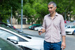 © JackF - Portrait of male who is standing satisfied with key near his car outdoor.