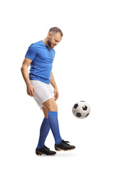 Full length shot of a footballer in a blue top and white shorts kicking a ball