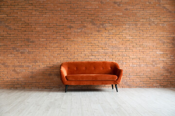 Red sofa near brick wall in empty room