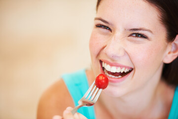 Canvas Print - Enjoying a baby tomato. Portrait of a beautiful young woman eating a baby tomato.