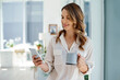 © Mikolette Moller/peopleimages.com - Good news just came in. Cropped shot of an attractive young businesswoman drinking coffee and using her cellphone inside of an office.