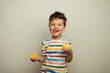 little boy eating lemon, sour taste, makes grimace, facial emotions negative, in white striped T-shirt, isolated white background, copy space.