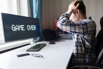 Wall Mural - male gamer loosing a video game, game over text on the screen