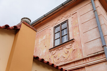 Kutna Hora, Czech Republic, 5 March 2022: Narrow picturesque street with colorful renaissance and baroque buildings in center in medieval city, vintage window with wooden frame in pink house