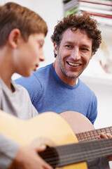 Sticker - Plucking with pride. Shot of a father teaching his son the guitar.