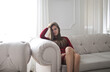 © Cavan Images - young woman sitting on a sofa at home