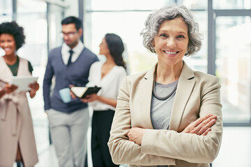 Poster - Im always around and ready to get my hands dirty. Portrait of a businesswoman standing in an office with her colleagues in the background.