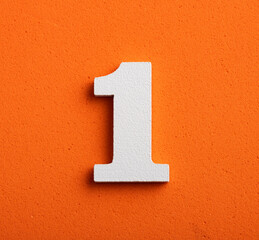 one, white wooden number on orange background