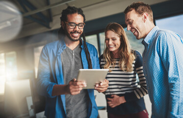Aufkleber - Fostering creativity. Shot of three young designers talking over a digital tablet in their office.