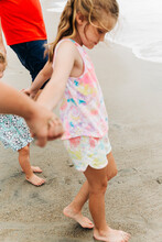 Young Girl Holding Hands With Her Family While On The Beach