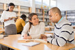 © JackF - Positive hispanic man and woman spending time together in library, talking, reading books and making notes
