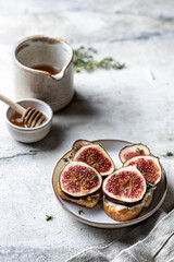 Two sandwiches with figs, cheese, thyme and honey with linen napkin on textured background