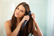 © Alexandra W/peopleimages.com - Straightening her hair for that sexy look. Portrait of an attractive woman straightening her hair with a flat iron.