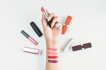 Wall Mural - Woman holding the beautiful lipstick and apply on her hand with beauty and cosmetic products on white background