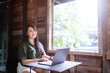 © Thinapob - Happy of asian freelance people business female  wearing brownish green dress stylish hipster casual working with laptop computer with coffee cup beside the window of a wooden house background