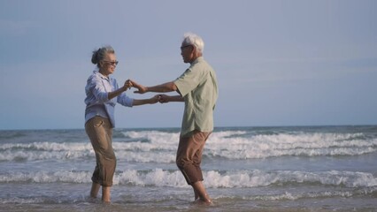 Wall Mural - Happy Asian senior man and woman couple smile dancing resting relax on the beach honeymoon family sunny day, Romantic elderly enjoy travel summer vacation, plan life insurance at retirement couple