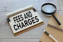 FEES CHARGED Wooden Light Table. Magnifying Glass.text On Open Notepad