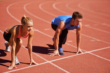 Ill take you on. Shot of two young people getting ready to race on an athletics track.