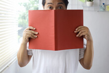 Man Peeking And Covering His Face From Behind Red Book For Book Mock Up