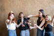 Group of young adult girlfriends drinking sparkling wine and firing sparklers, celebrating together on background indoors. Concept of female friendship and celebration holidays