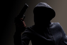 Photo Of A Creepy Horror Criminal In Black Hoodie Holding Revolver Gun.