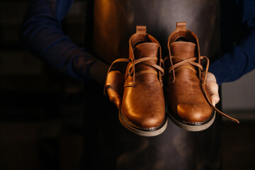 Photo of a pair of quality men's leather shoes in the hands of the master who made them.