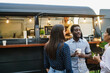 © DisobeyArt - Multiracial people having fun drinking in front of food truck outdoor - Focus on african man face