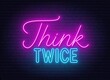 Think Twice neon lettering on brick wall background.