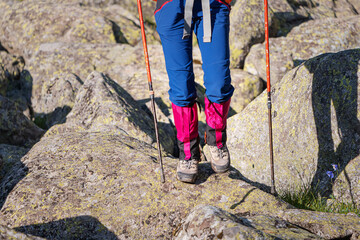 hiker wears waterproof gaiters over trekking boots walking with hiking sticks. clothing and equipmen