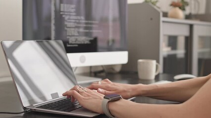 Slowmo closeup of unrecognizable female programmer typing program code on laptop connected to pc computer, sitting at desk in home office