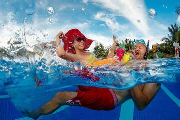 Young couple have a fun in swimming pool with cocktails