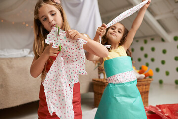 Wall Mural - Sisters make the best friends. Shot of two little girls having fun making dresses.