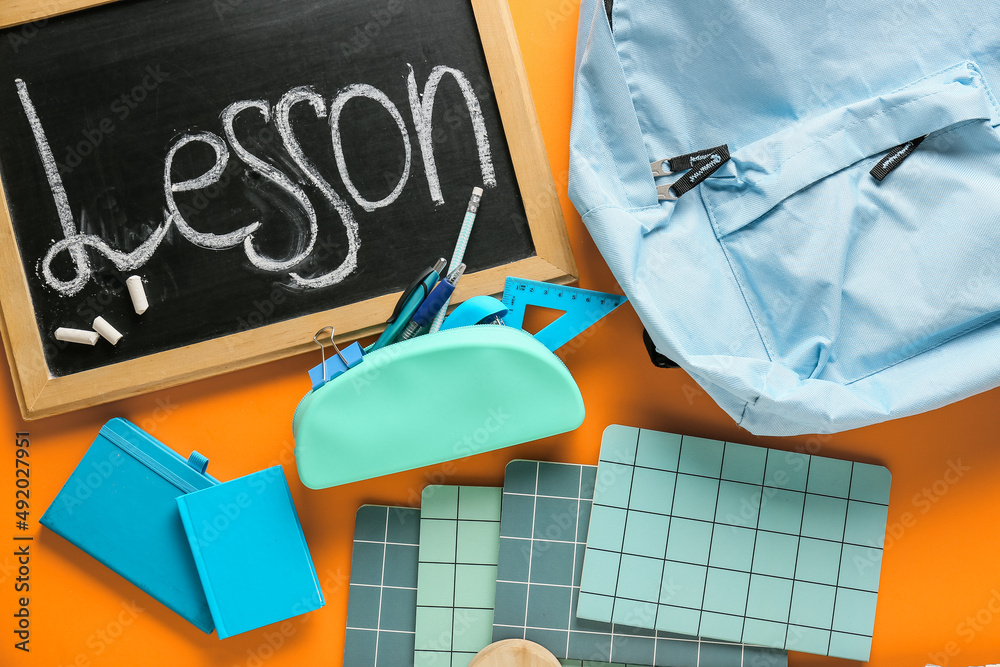 Chalkboard with word LESSON, backpack and stationery on color background