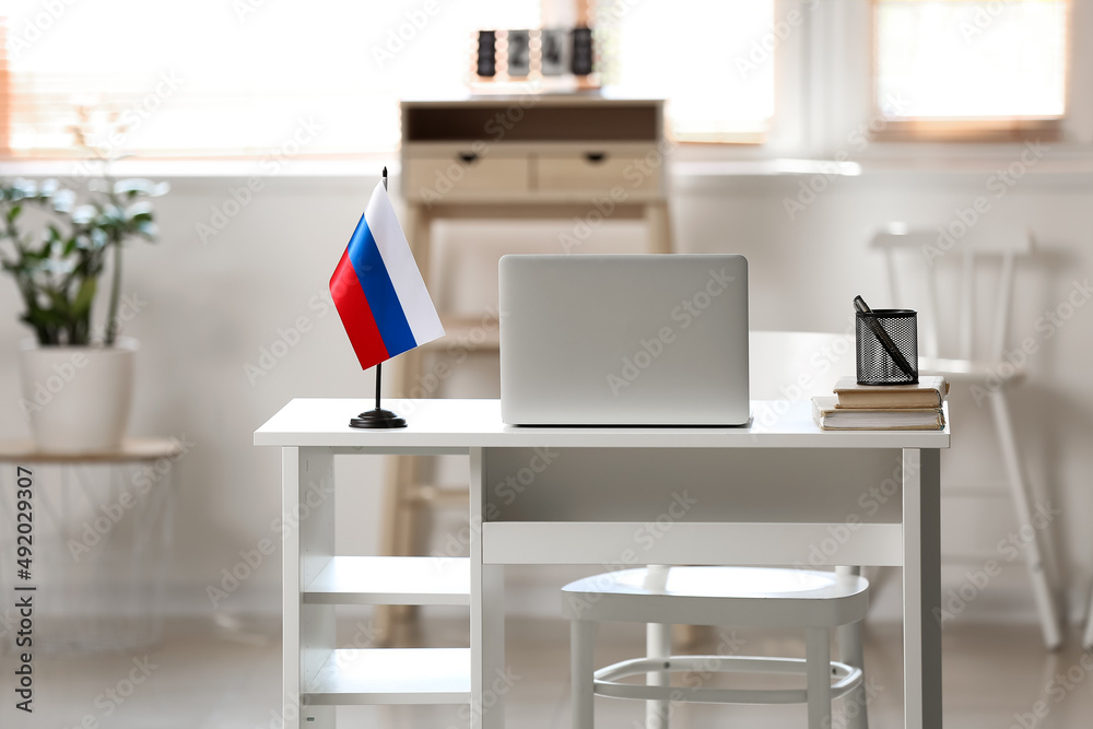Comfortable workplace with Russian flag and modern laptop in light room