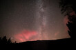 Rot glühender Himmel nachts mit Sterne Milchstraße und Sternschnuppe am großen Arbersee im bayerischen Wald, Deutschland