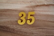 Golden Arabic numerals on a real brown and white wooden floor number 35