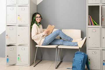 Canvas Print - Beautiful female student reading book while sitting near locker at the university