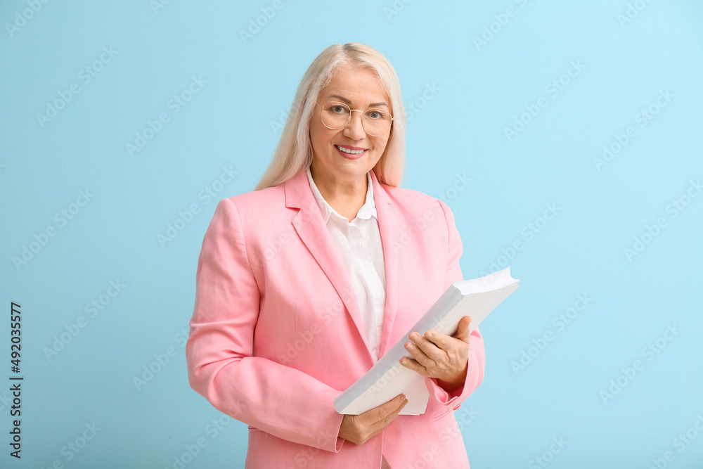 Mature secretary with papers on blue background