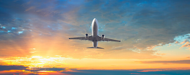 Airplane flying over tropical sea at sunset