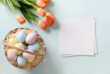 Easter Greeting Card With Eggs In Wicker Basket And Tulips On Blue Background. View From Above.Copy Space.