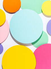 Fun bright coloured mosaic of paper circles in pink, blue, yellow and purple colours. Minimalist background in pastel tones. Creative conceptual template for styling and design. Mock up for text.