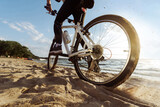 man on a bicycle slowly moving along a sandy beach.