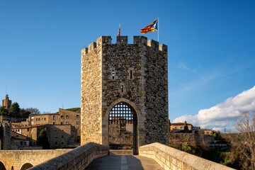 Wall Mural - Besalu historic medieval city with Catalonia flags on the stone bridge tower crossing El Fluvia river, in Spain